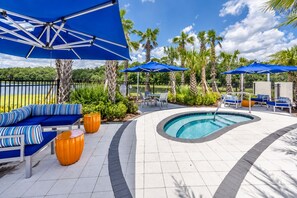 A poolside area with blue umbrellas, lounge chairs, and a curved pool.