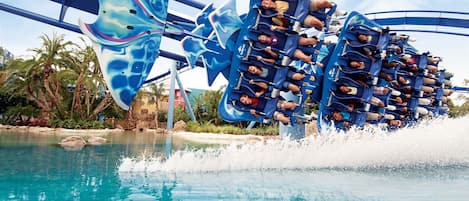 A water ride with a large blue and white structure, surrounded by a pool and palm trees.