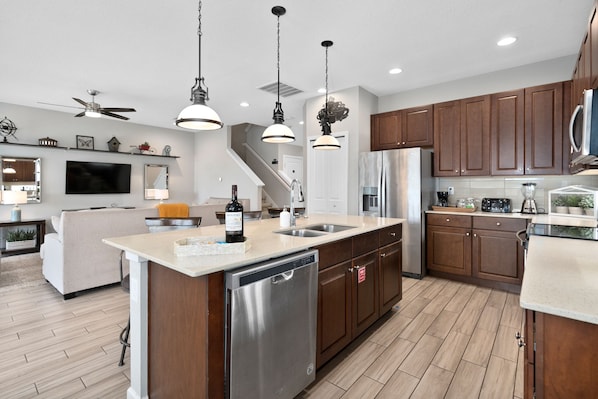 Une cuisine moderne avec des meubles en bois, des appareils électroménagers en acier inoxydable et des luminaires suspendus.