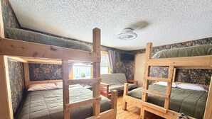 Ein Zimmer mit Stockbetten, einem Holztisch, einem Stuhl und einem Fernseher.