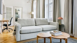 A modern living room with a grey sofa, a small round table, and a lamp.