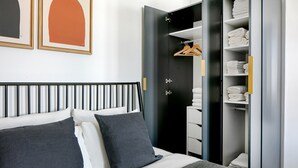 A modern bedroom with a bed, a wardrobe, and a closet with hanging clothes.