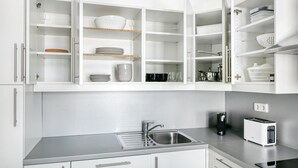 A modern kitchen with white cabinetry, a stainless steel sink, and a built-in toaster.
