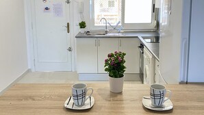 Una cocina moderna con armarios blancos, una ventana y un lavamanos. Hay dos tazas sobre la mesa.