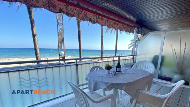 Un espacio de estar al aire libre cubierto con una mesa y sillas, con vistas a una playa.