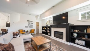 A modern living room with a fireplace, a large TV, and a cozy seating area. - Swanky Downtown Cowboy (Paso Robles)