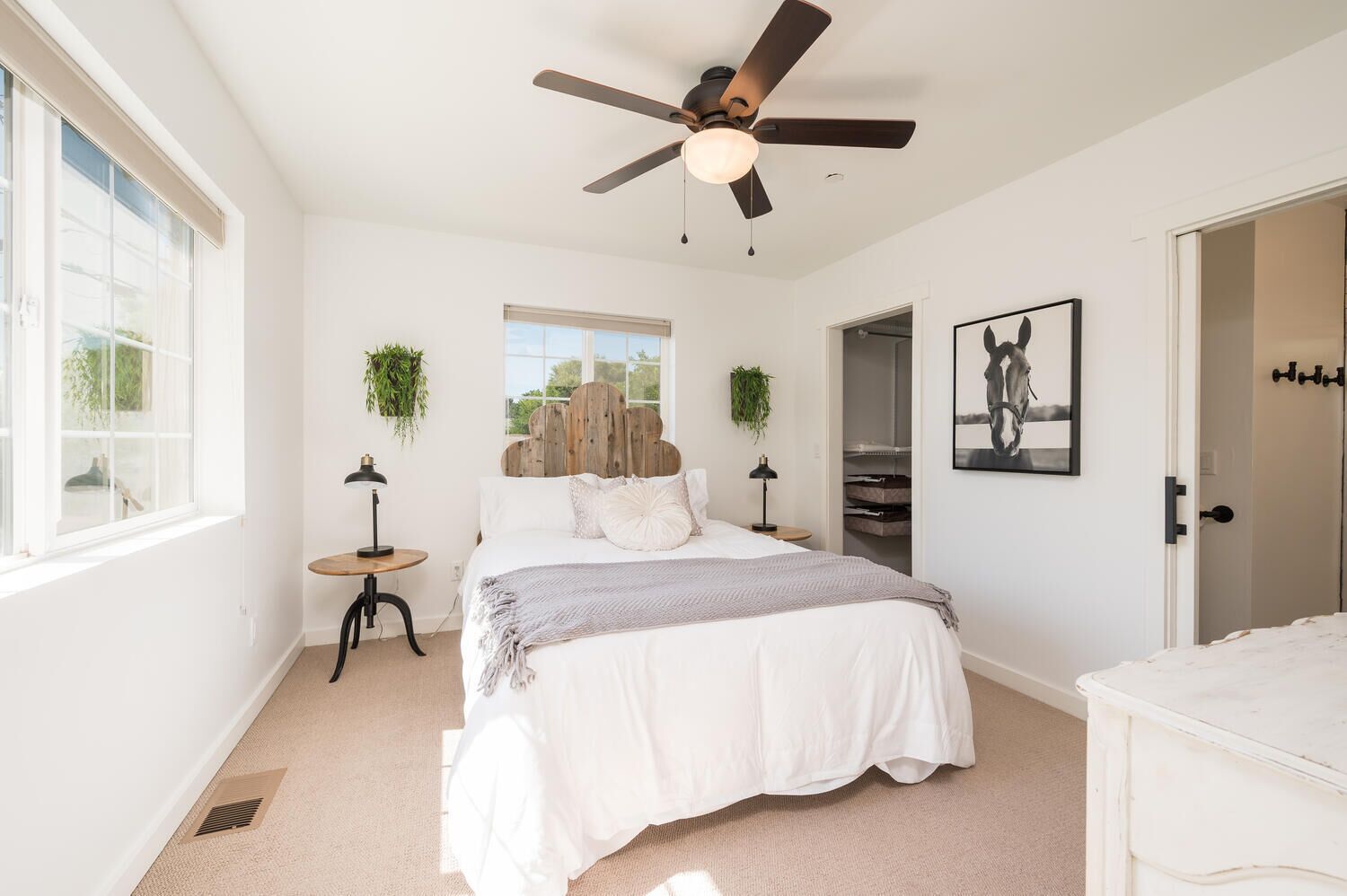 A bedroom with a bed, a ceiling fan, a window, a door, and a closet.