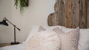 A bed with a wooden headboard, white bedding, and decorative pillows. - Swanky Downtown Cowboy (Paso Robles)