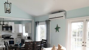 A modern kitchen with white cabinets, a dining area with a table and chairs, and a living room with a sofa and a star decoration on the wall. - La Nueva Beach home two minute walk to beach & 1 minute walk to the golf course (Abaco)