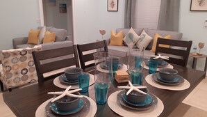 A dining area with a dark wooden table set for six, featuring blue glassware and starfish centerpieces. - La Nueva Beach home two minute walk to beach & 1 minute walk to the golf course (Abaco)