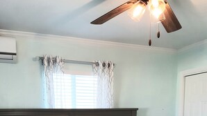 A bedroom with a bed, a ceiling fan, a window with curtains, and a door. - La Nueva Beach home two minute walk to beach & 1 minute walk to the golf course (Abaco)