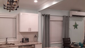 A compact kitchen with white cabinets, a built-in dishwasher, a granite countertop, and a dining area with a table and chairs. - La Nueva Beach home two minute walk to beach & 1 minute walk to the golf course (Abaco)
