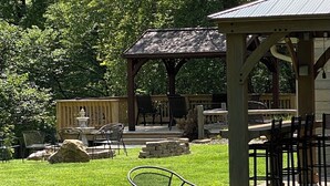 Un espace extérieur aménagé avec une terrasse, un belvédère, des sièges en pierre et un foyer.