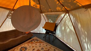 A tent interior with a large white circular object, a small table, and a patterned rug.