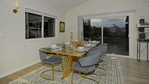 A dining area with a glass-top table, grey upholstered chairs, and gold accents. - Bohemian Rhapsody Retreat ~ 2 Bed 3 Bath With Game and Theatre Room (Sedona)