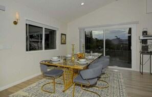 A dining area with a glass-top table, grey upholstered chairs, and gold accents. - Bohemian Rhapsody Retreat ~ 2 Bed 3 Bath With Game and Theatre Room (Sedona)