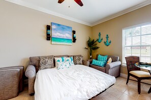 A bedroom with a large bed, a sofa, a dining table, and a window with blinds. - Coastal-themed home near the ocean with pool, AC & fast WiFi (South Padre Island)