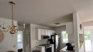A modern kitchen with white cabinets, stainless steel appliances, and a dining area with a wooden table and chairs. - Sunlit townhome at Ocean Edge Resort in Brewster- central A/C, pool privilege's (Brewster)
