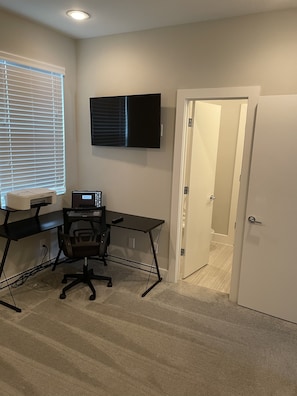 Work in comfort with a desk, computer, and printer, plus a comfortable office chair and flat-screen TV.
