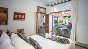 Une chambre avec un lit, une vue sur l’espace extérieur et une porte donnant sur une terrasse.