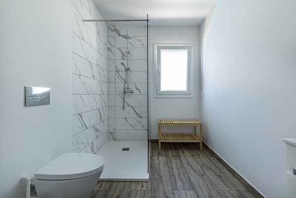 Une salle de bain moderne équipée d’une douche, de toilettes et d’un banc en bois.