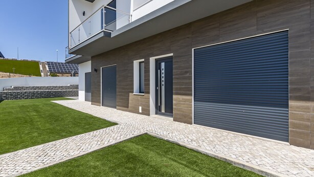 Un bâtiment moderne à deux étages, doté d’un toit plat, de grandes portes de garage et d’un balcon.