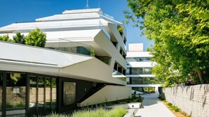 A modern multi-story building with a unique angular design, featuring a prominent entrance with a glass facade and a sign that reads "MARINA". - Fenyves by Interhome (Balatonszemes)