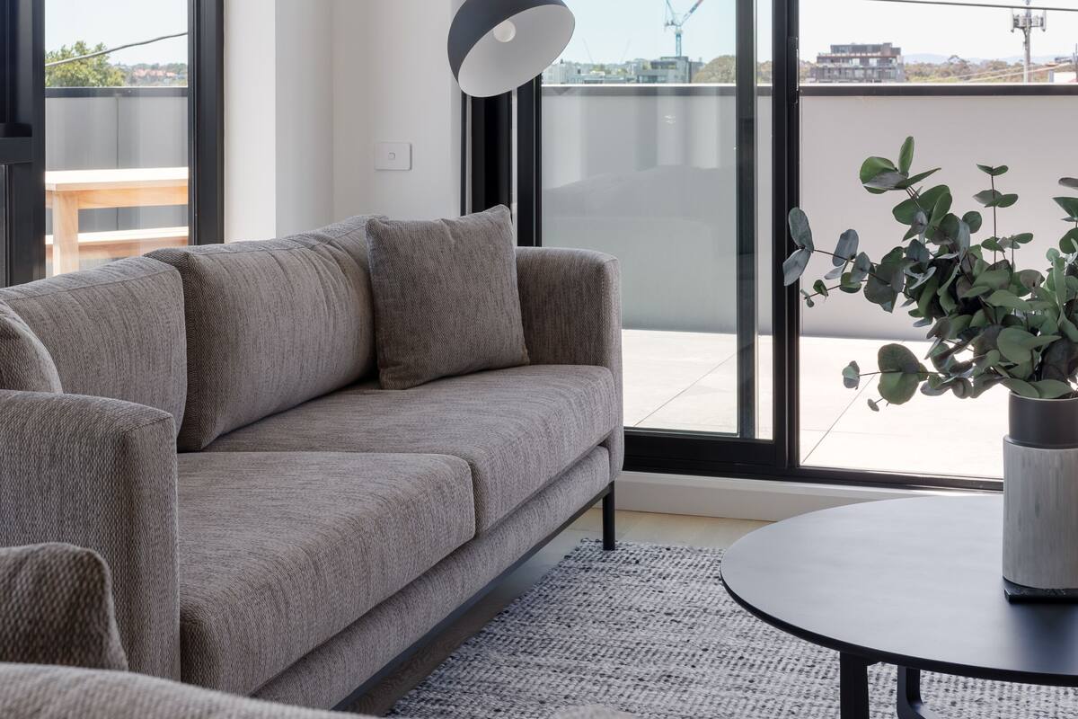 A modern living room with a sofa, a round table, and a potted plant.