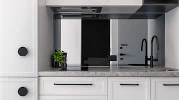 A modern kitchen with white cabinetry, black handles, and a stainless steel range hood.