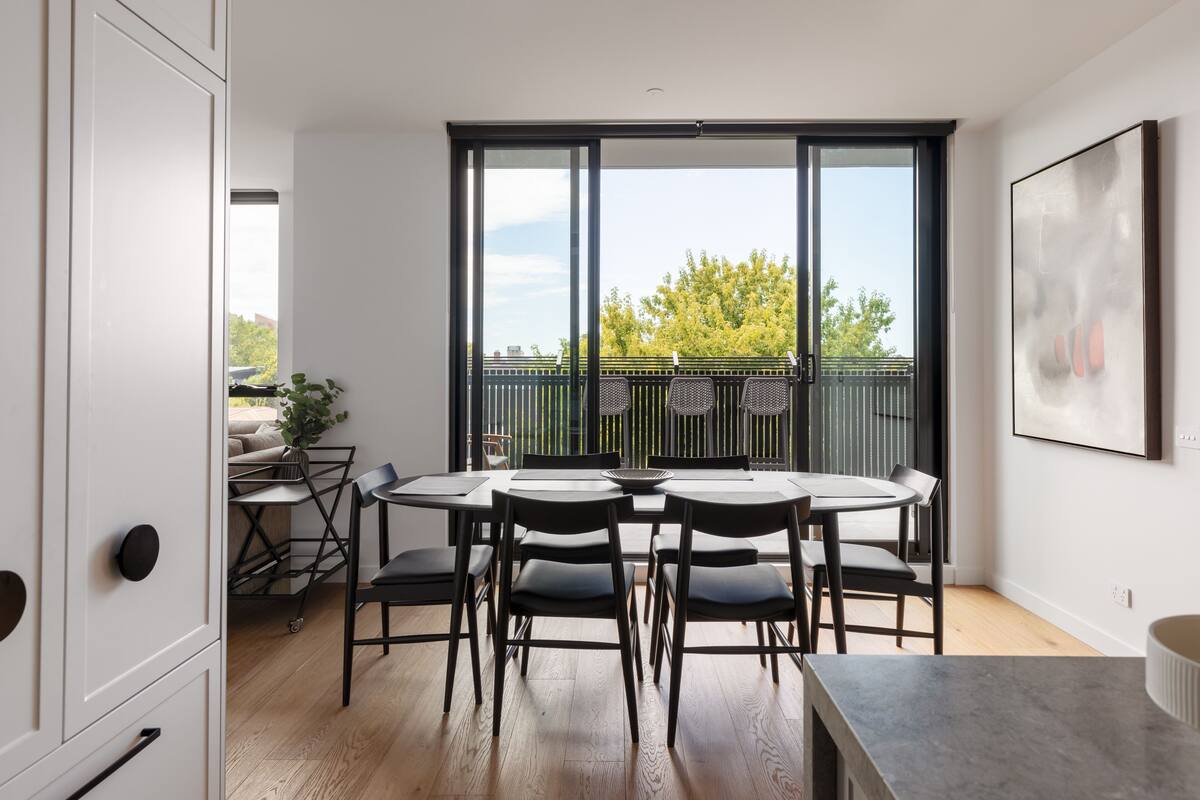 A modern dining area with a large window, a dining table with chairs, and a view of the outdoors.