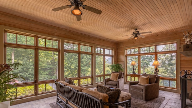 A spacious room with large windows, a ceiling fan, and a fireplace.