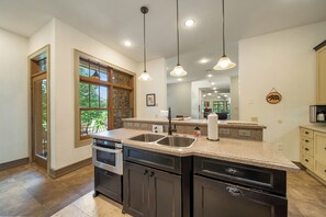 A modern kitchen with granite countertops, stainless steel appliances, and pendant lighting.
