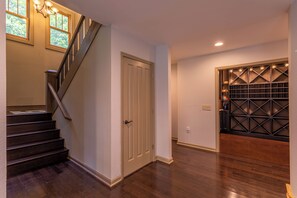 A staircase leading to a door, a wine rack, and a wooden floor.