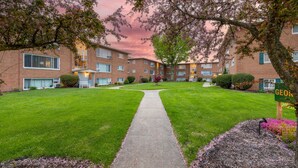 A residential building with a central pathway, surrounded by well-maintained lawns and trees.
