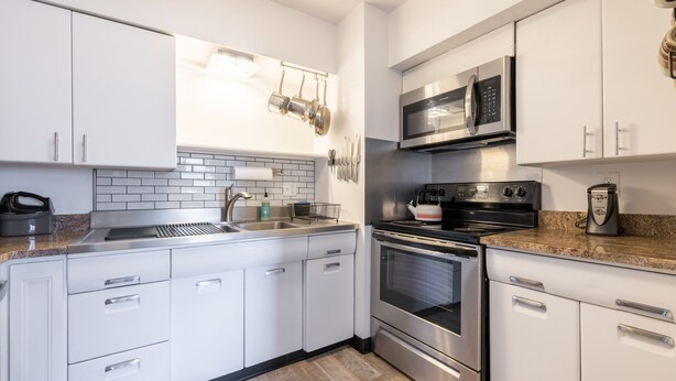 A modern kitchen with white cabinets, stainless steel appliances, and a granite countertop.