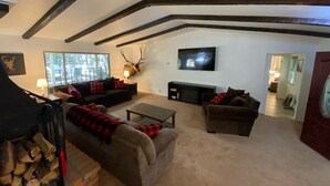 Un salon chaleureux avec une cheminée, une tête de cerf accrochée au mur et un téléviseur.