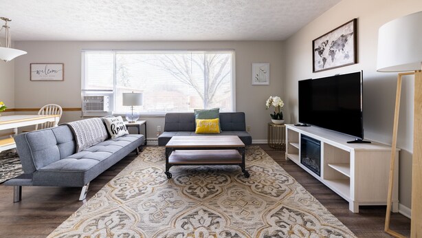 A modern living room with a sofa, coffee table, TV, and a patterned rug.