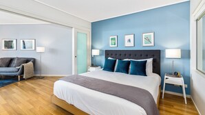 A modern bedroom with a large bed, a sofa, and a small table with lamps. - PEP 4305/6 - 2 Bedroom Apartment (Kingscliff)