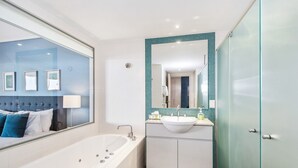 A modern bathroom with a large bathtub, a vanity with a sink, and a mirror. - PEP 4305/6 - 2 Bedroom Apartment (Kingscliff)