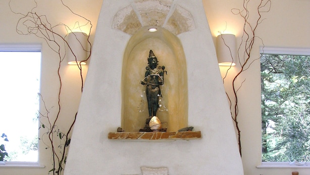 A fireplace with a stone surround, a decorative figure above it, and two wall-mounted lights. - Serene Montclair Getaway (Oakland)