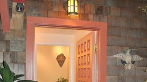 A wooden door with a decorative glass panel, a small potted plant, and a wall-mounted light fixture. - Serene Montclair Getaway (Oakland)