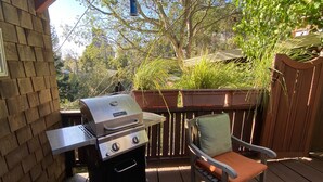 A barbecue grill on a wooden deck with a chair and a potted plant. - Serene Montclair Getaway (Oakland)