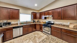 A kitchen with granite countertops, stainless steel appliances, and wooden cabinets. - Private House with Pool and Spa (Desert Hot Springs)