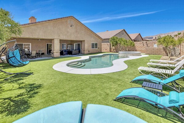 A backyard with a swimming pool, lounge chairs, and a hanging chair. - Private House with Pool and Spa (Desert Hot Springs)