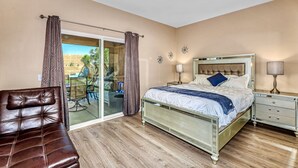 A bedroom with a bed, a nightstand, a chair, and a sliding glass door to an outdoor area. - Private House with Pool and Spa (Desert Hot Springs)