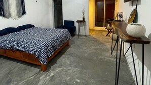 Une chambre à coucher comprenant un lit, un bureau, une chaise, un téléviseur et une porte donnant sur un balcon.