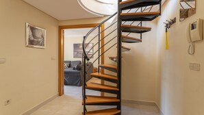 Un escalier en colimaçon avec des marches en bois et des rampes en métal, situé dans un couloir.