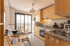 Une cuisine moderne dotée de plans de travail en granit, d’appareils électroménagers en acier inoxydable et d’armoires en bois.