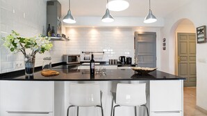 A modern kitchen with a large island, white cabinetry, stainless steel appliances, and pendant lighting.
