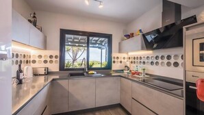 A modern kitchen with a built-in oven, a window with a view, and a countertop with various items.